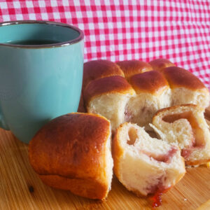 Buchteln auf einem Holzbrett mit Tee an der Seite.