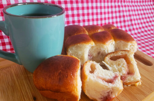 Buchteln auf einem Holzbrett mit Tee an der Seite.