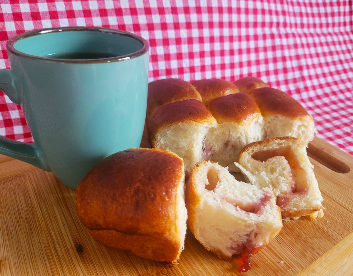 Buchteln auf einem Holzbrett mit Tee an der Seite.