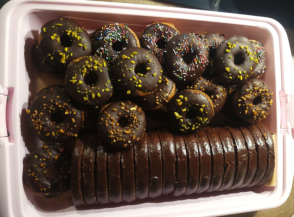 Ofengebackene Donuts und Schokoladenkuchen in einer Kuchenbox.